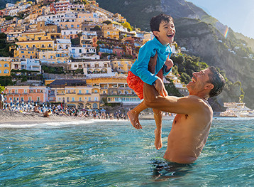Father lifting son while in the ocean. Summer.