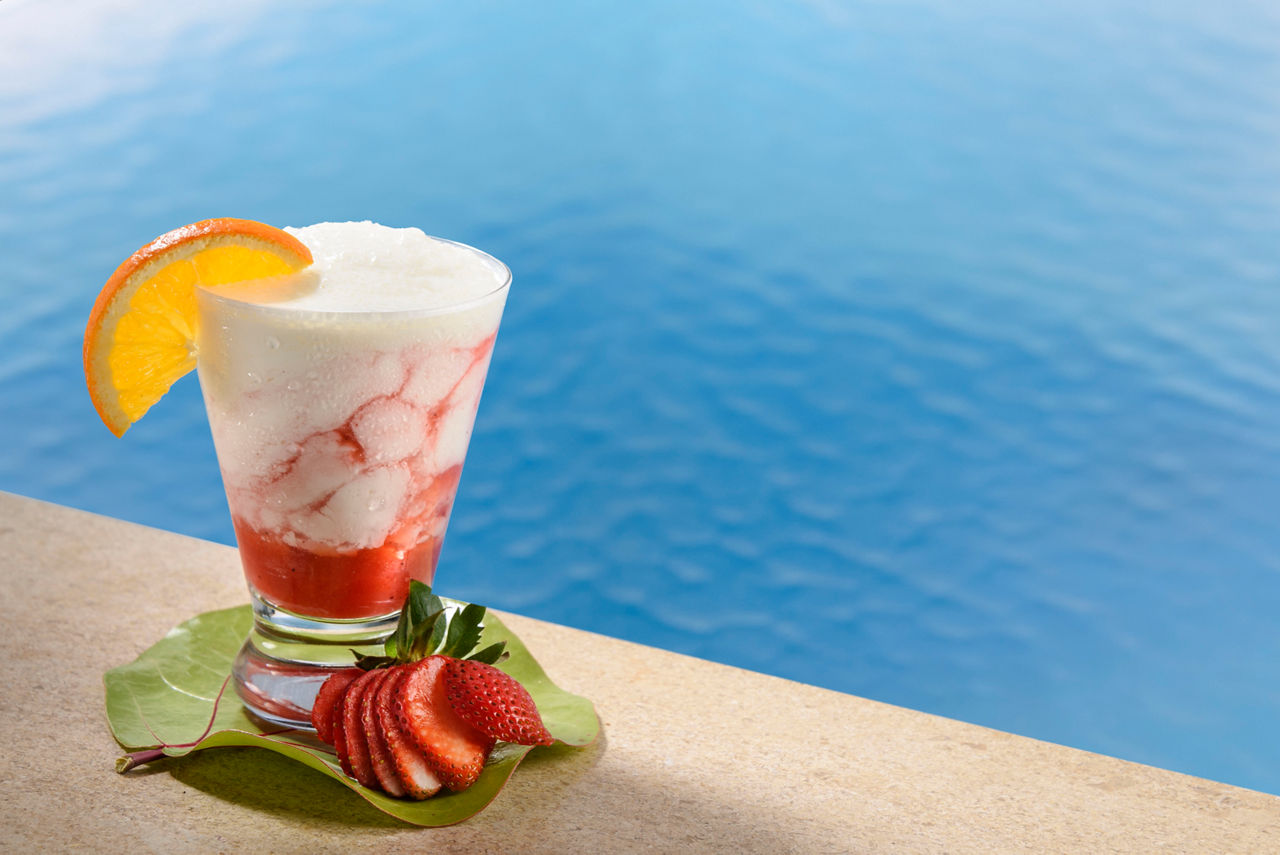 F&B, Drinks, cocktails; beverage package, 2016 Beverage shoot, Strawberry Lava Flow, mixed drink, frozen cocktail, strawberry and orange garnish, pool water in background,