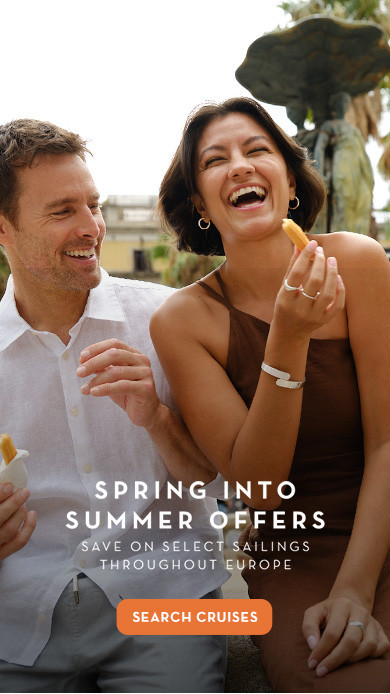 Two people enjoying a snack outdoors in a European plaza with palm trees and historic buildings in the background