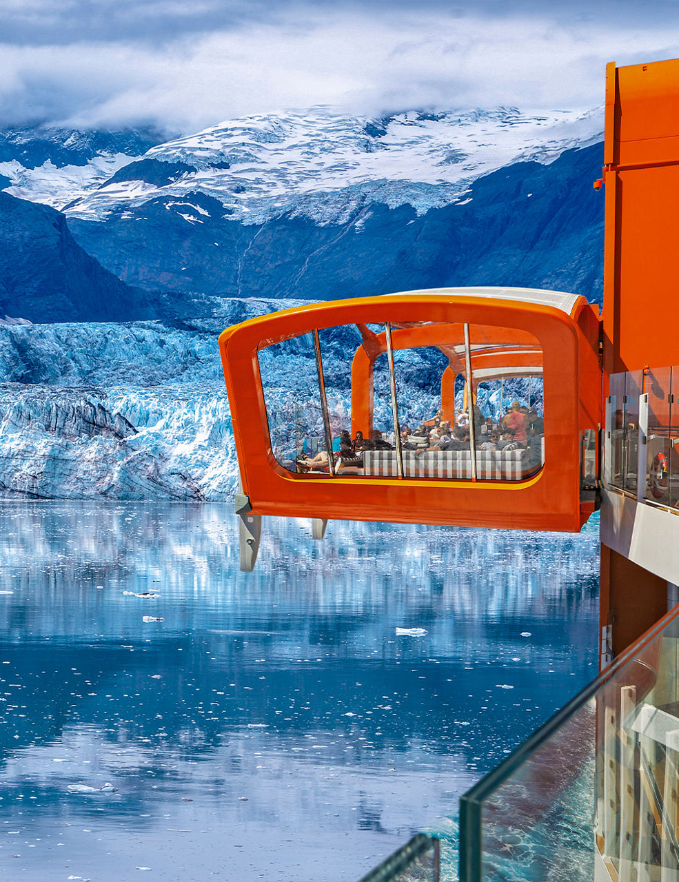 Two people sitting together at the edge of a tropical beach with turquoise water and lush green mountains in the background
