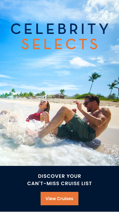 Two people splashing in shallow turquoise water along a sandy tropical beach with palm trees and clear skies.