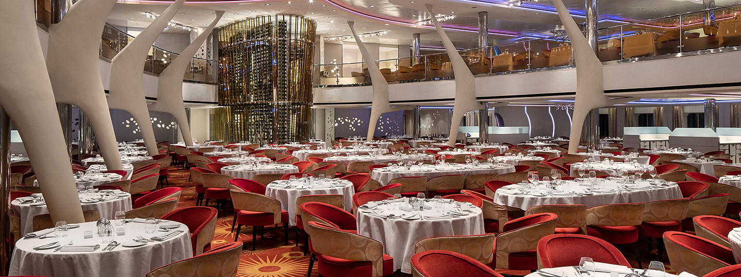 A beautiful fine dining restaurant with a glowing tower of wine bottles ready for evening service.