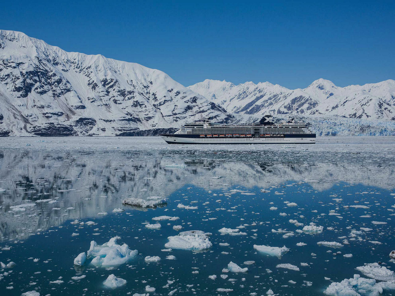 El azul gélido del glaciar Hubbard elevándose detrás de un barco de Celebrity Cruises.