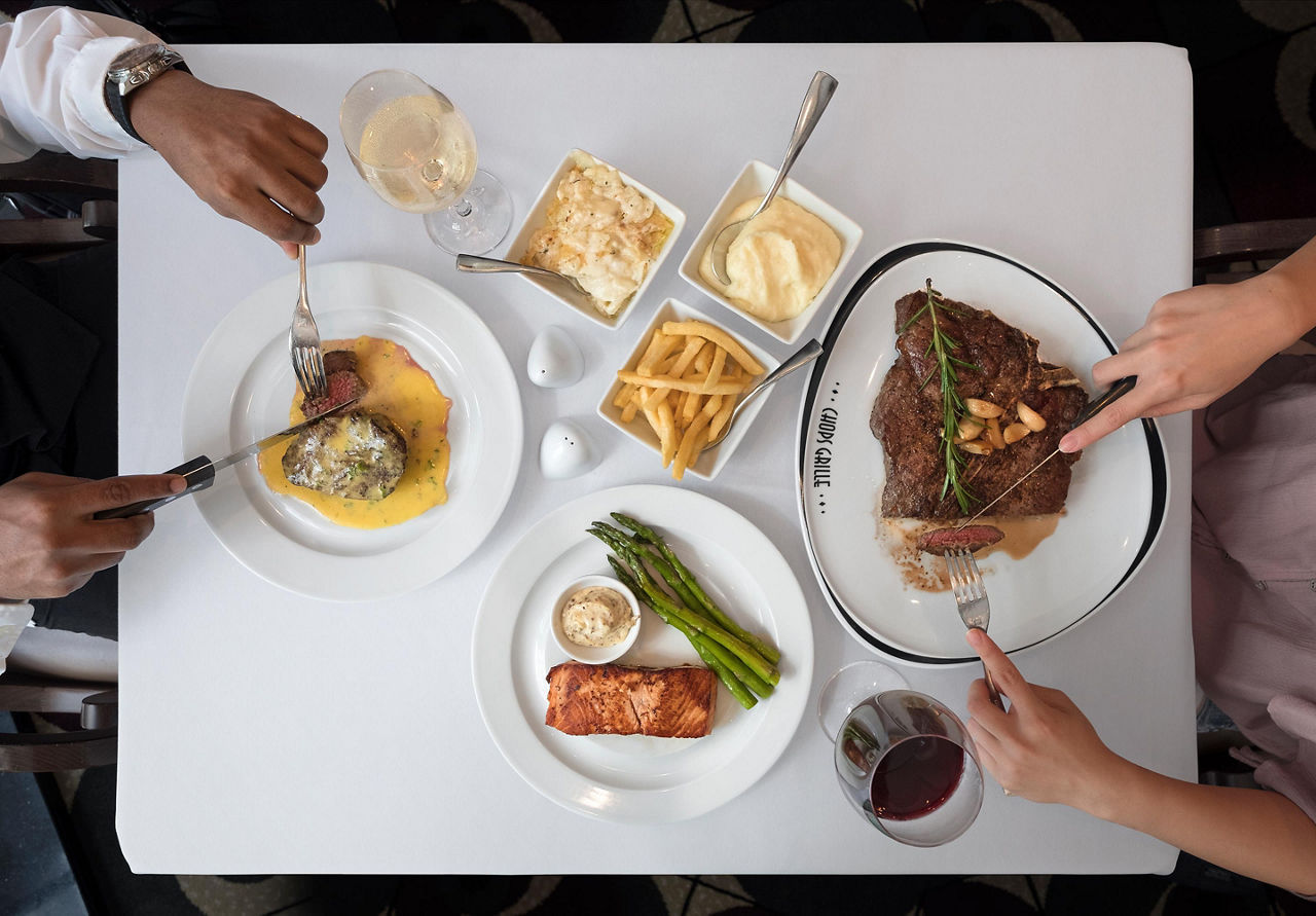 A top-down view of a couple enjoying dinner dishes at Chops Grille on a Royal Caribbean cruise ship