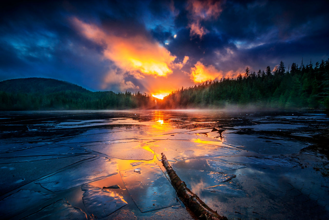 A fiery sunset is reflected on the frozen water of Ward Lake In Ketchikan, Alaska.