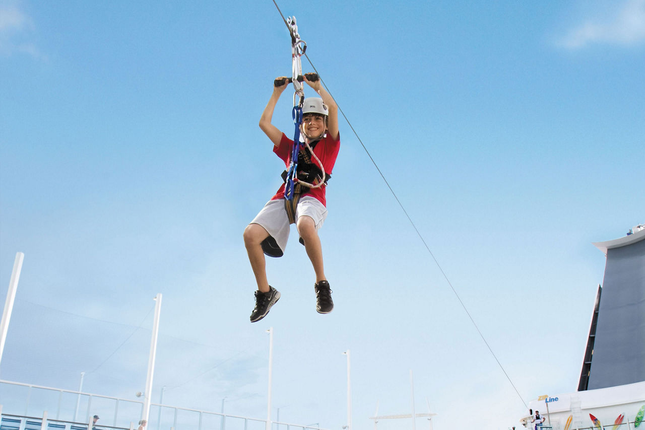 A boy riding a zip line on Oasis of the Seas