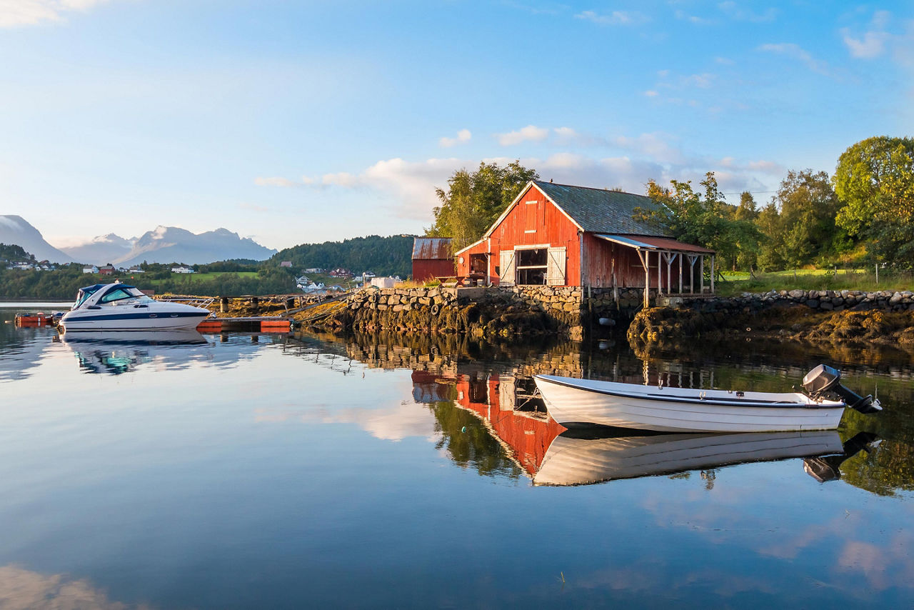 Two boats docked outside of a red fishing hut in Norway