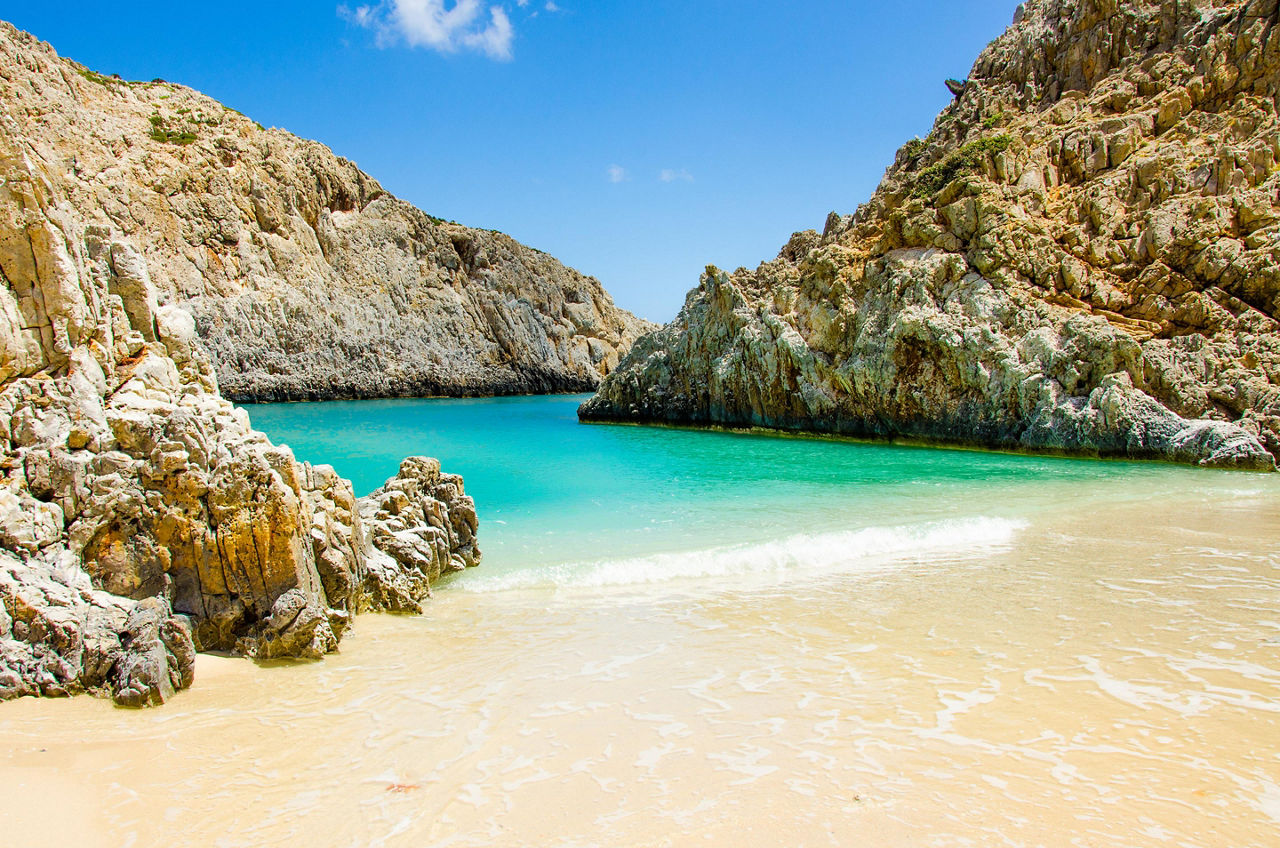 A beautiful pristine beach surrounded by rock formations in Crete