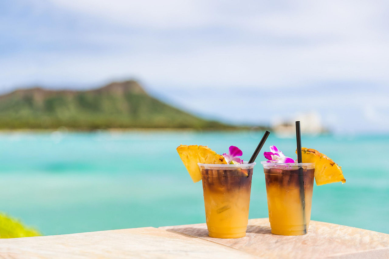 Two Mai Tai drinks with a blurred beach in the background