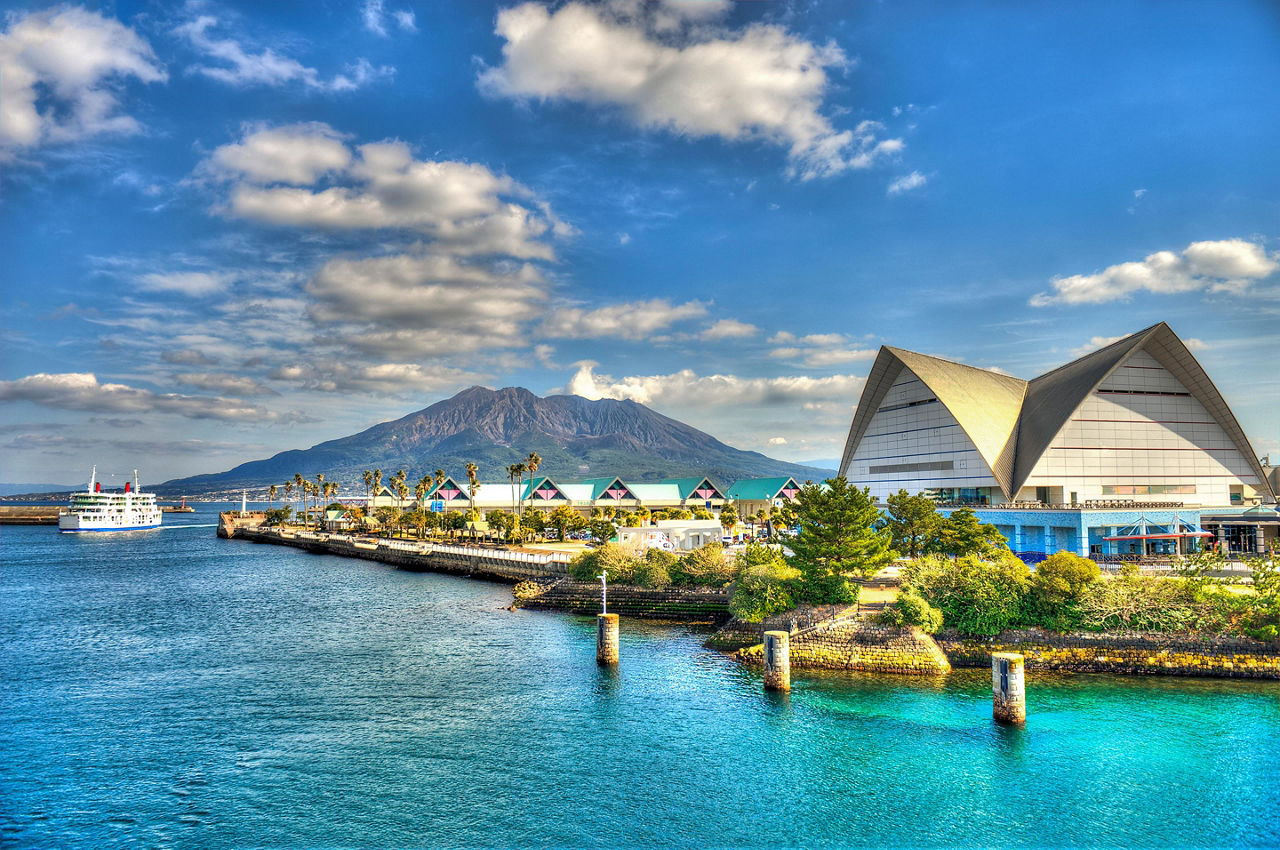 View from the ocean looking at the volcano and a modern building along the coast on a sunny cloudy day 