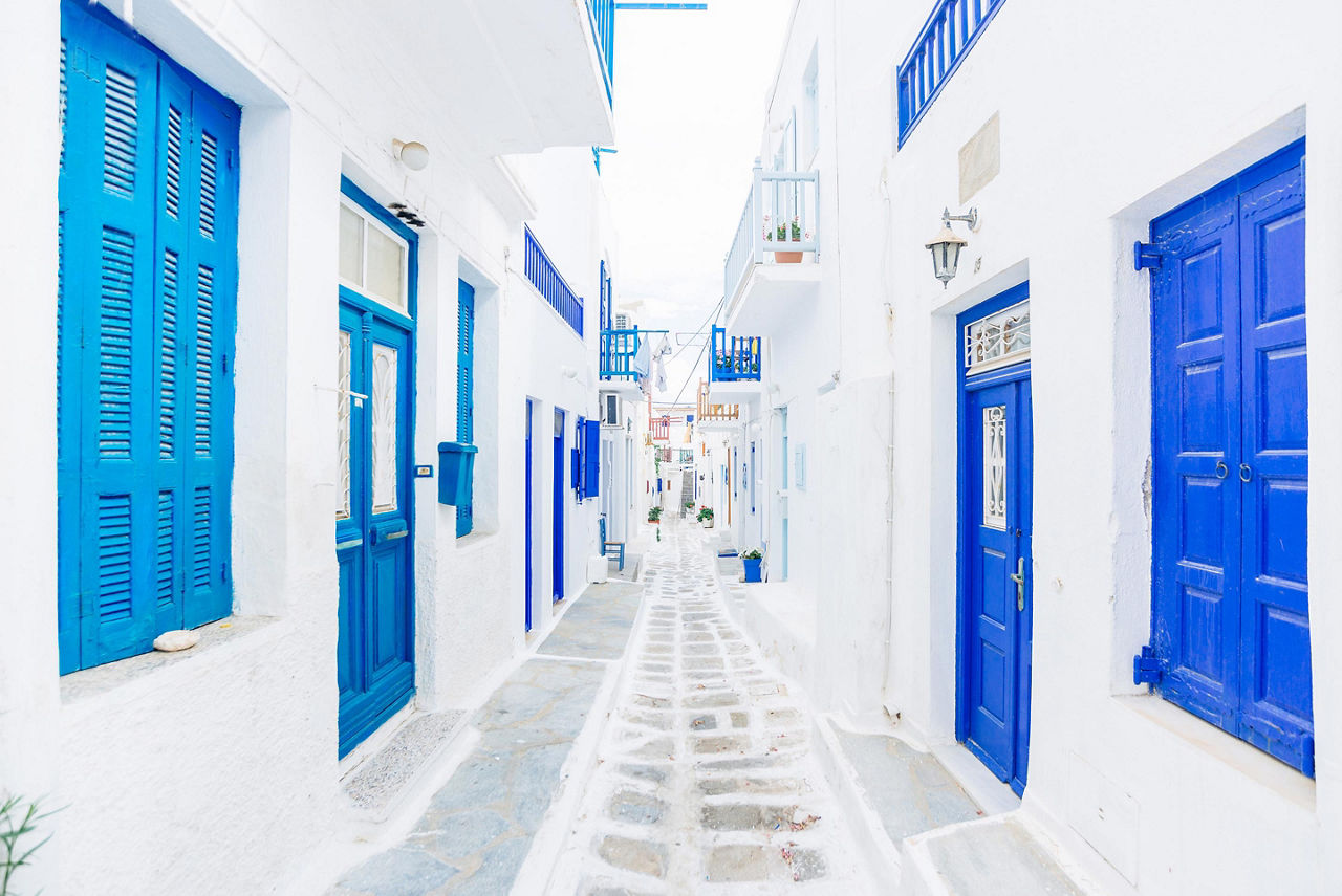 A street of white buildings with blue accents in Mykonos, Greece