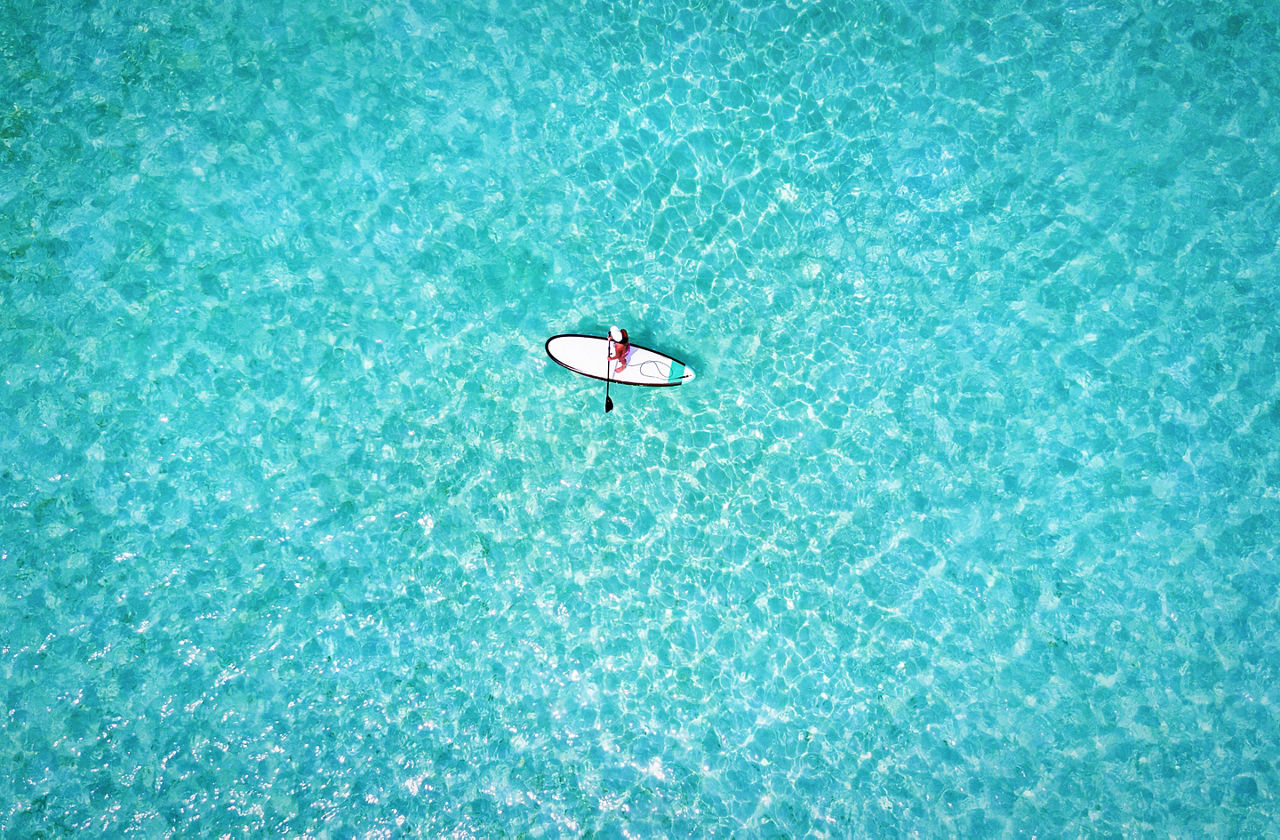 Woman on a stand up paddle boat over turquoise waters
