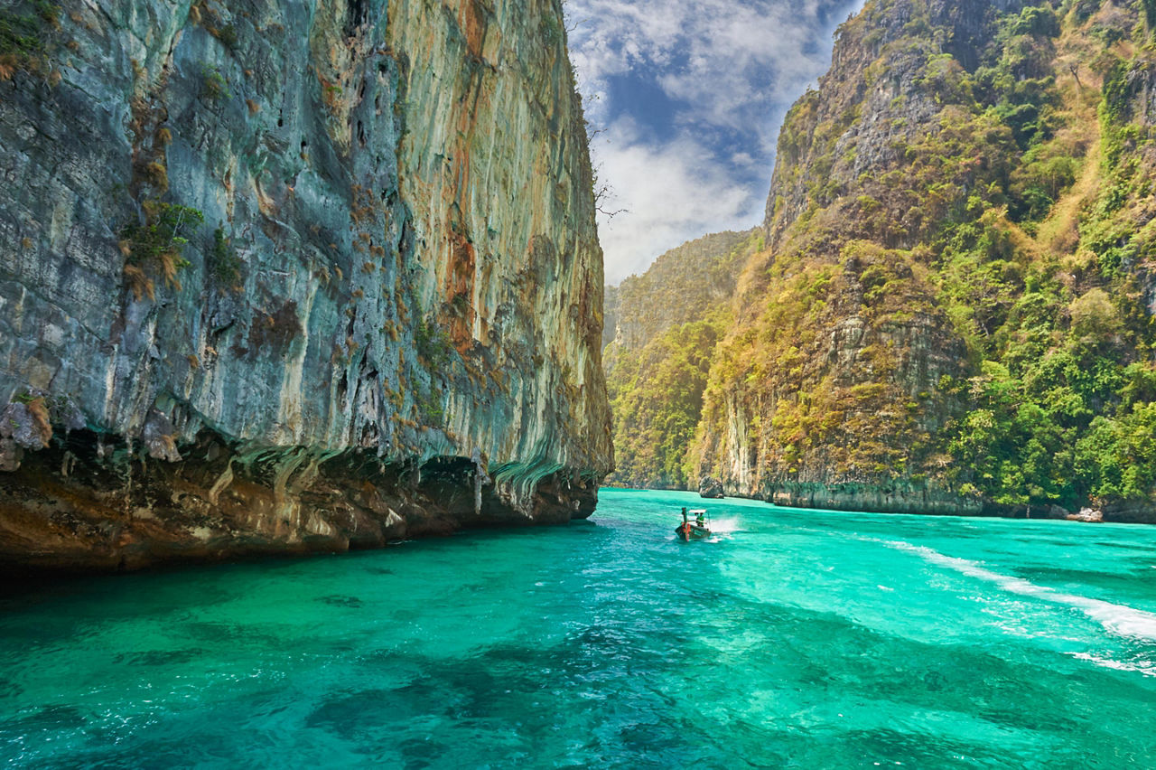 A longtale boat sailing through giant rocks in the ocean of Phuket, Thailand
