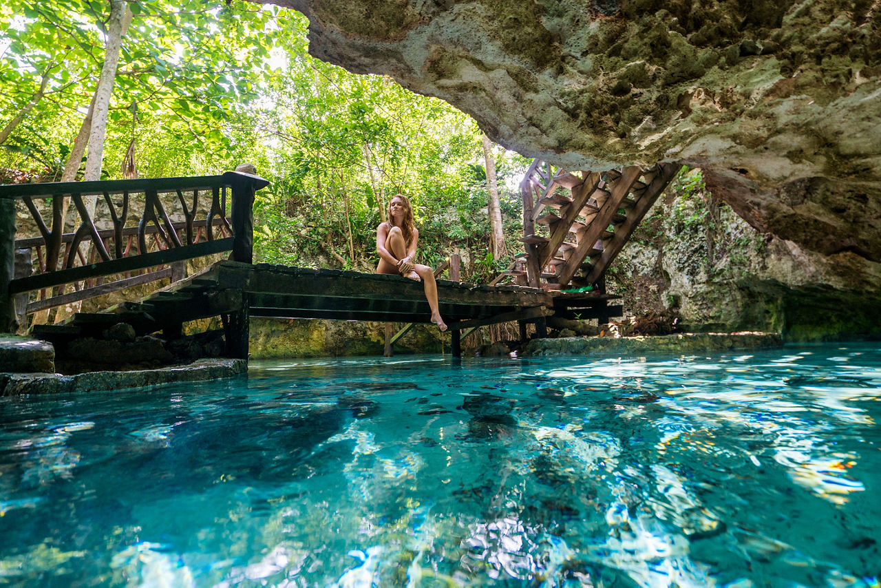 Costa Maya, Mexico, Yucatán, woman sitting on edge of walkway, bridge, over large underground lake, water