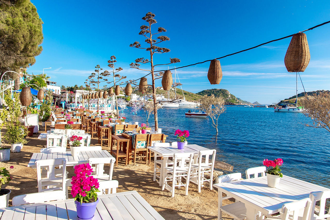 Restaurant or cafe and bougainvillea flowers on beach in Gumusluk, Bodrum city of Turkey. 