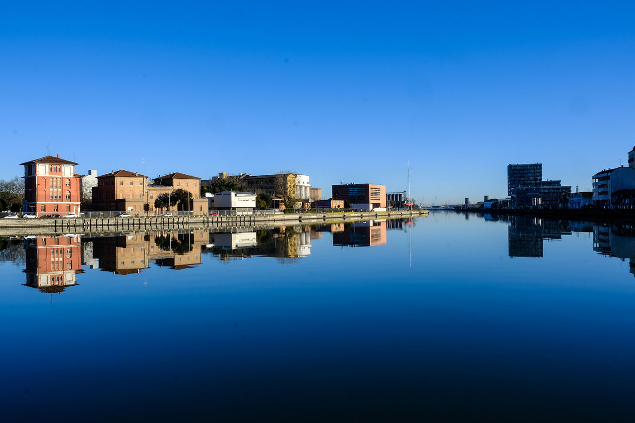Beutiful buildings reflection on Ravenna's darsena on a sunny day with blue sky. 
