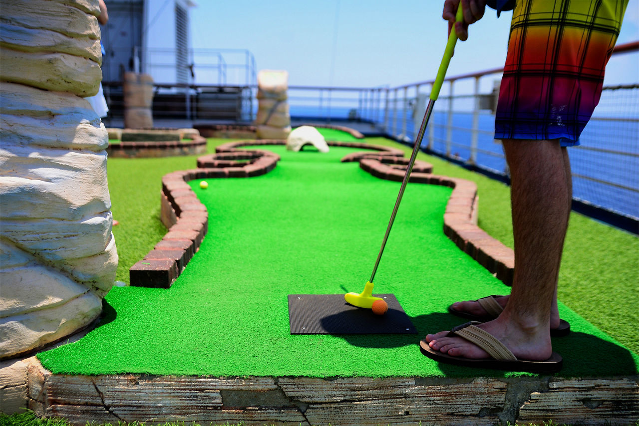 Man playing mini golf on a cruise ship open deck.