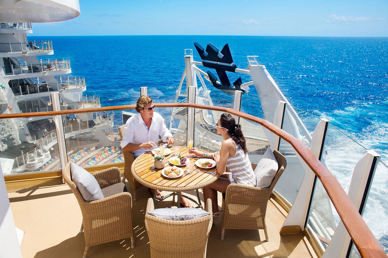 Allure of the Seas, Oasis Class, couple having lunch in balcony in AquaTheater Suite, ocean horizon in background, wicker table and chairs, blue sea, relaxing, enjoyment