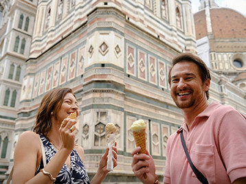 Two people eating gelato in front of the ornate marble façade of Florence’s cathedral complex.