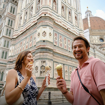 Two people eating gelato in front of the ornate marble façade of Florence’s cathedral complex.