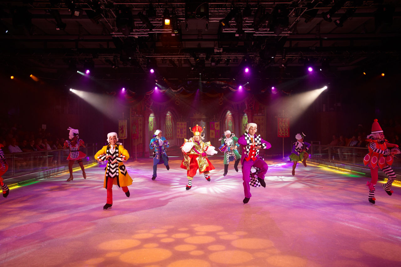 Performers dancing in colorful costumes during ice skating shows onboard a cruise.