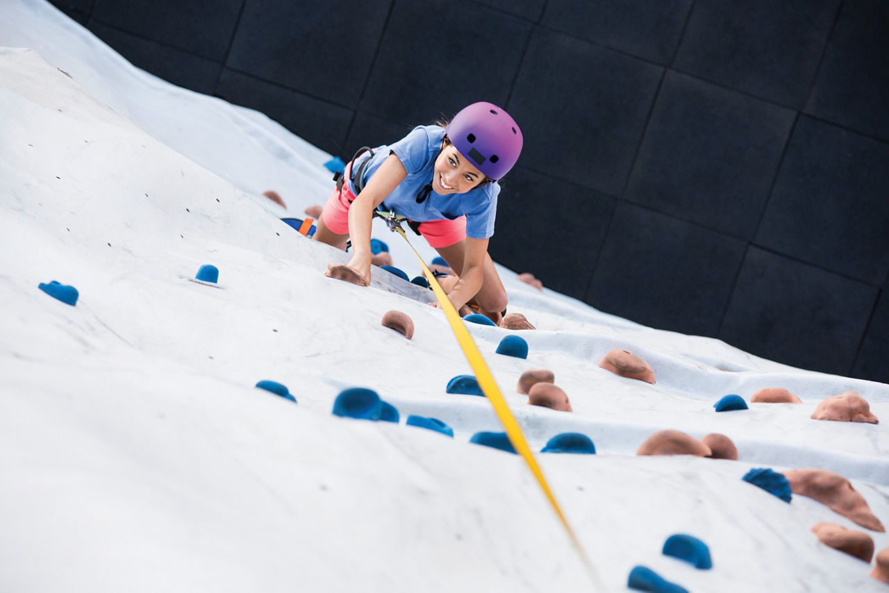 Young Woman Climbing Up the Rock Wall 