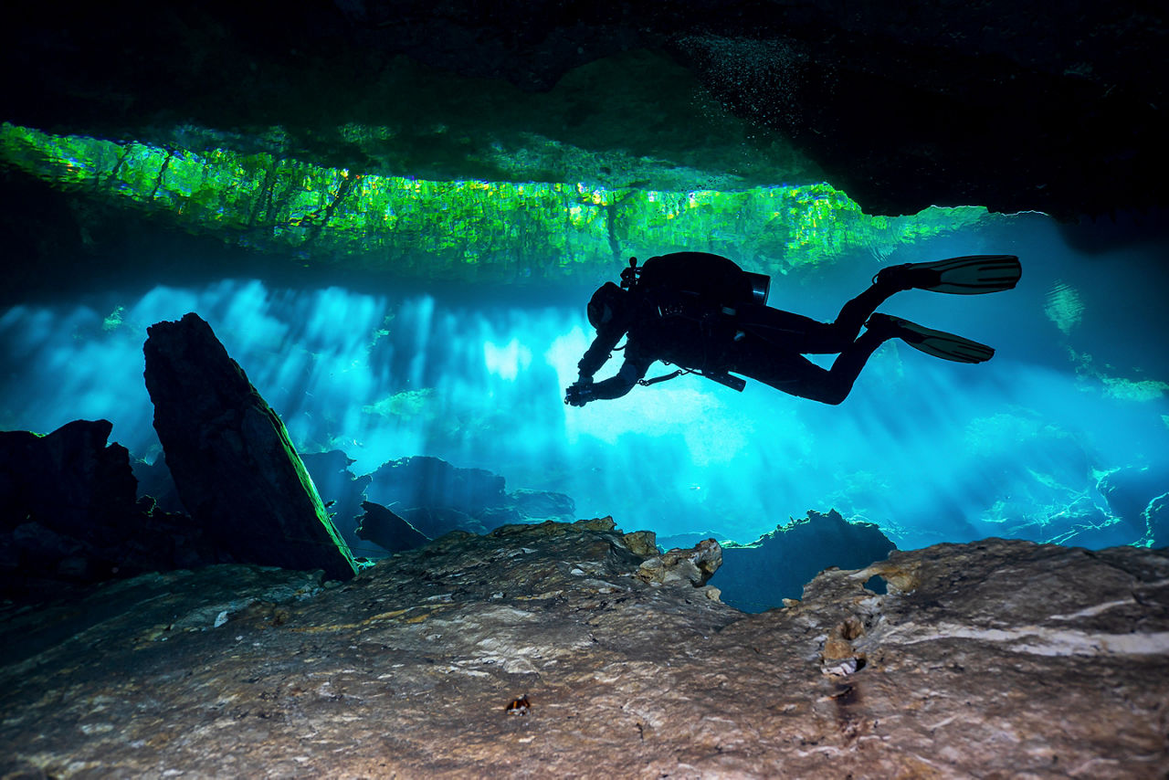 Cave Diver diving through the lights in a Cenote in Mexico