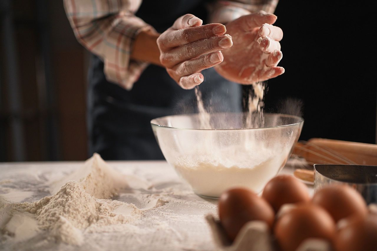 Close up of woman hands pouring flour into bowl while baking