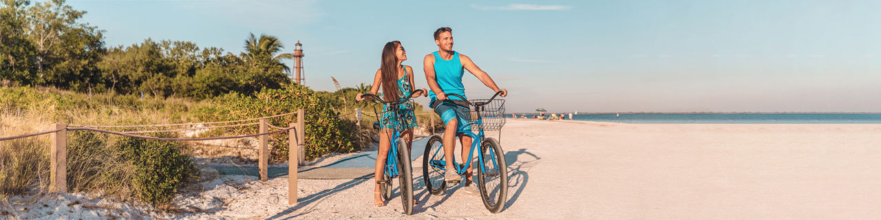 Couple riding bikes at Sanibel Island beach side.