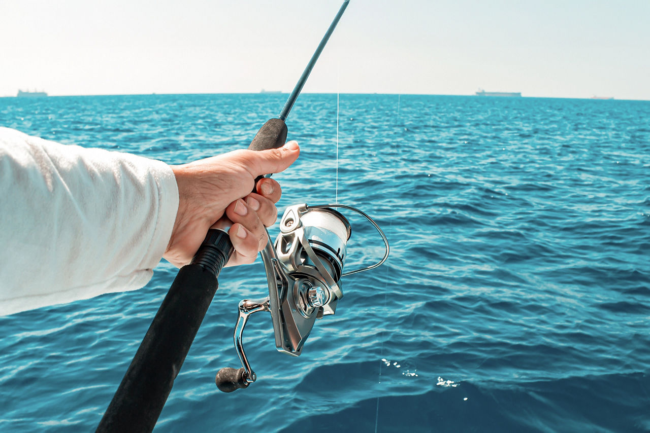 A fisherman hand firmly grips a fishing rod