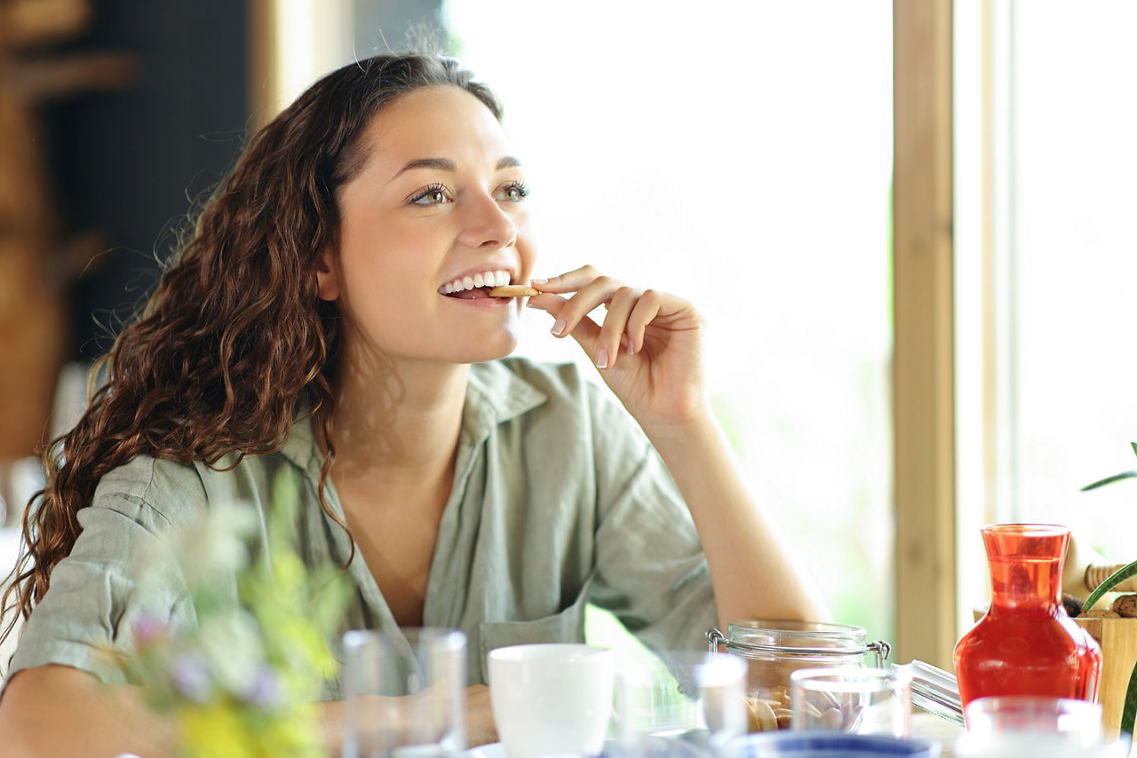 Happy woman eating cookie sitting in a restaurant