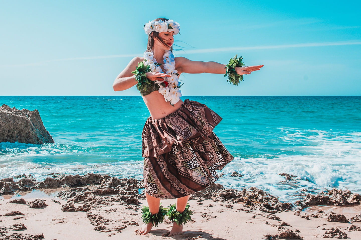 A hula dancer performs gracefully on a sandy beach. - Honolulu, Hawaii