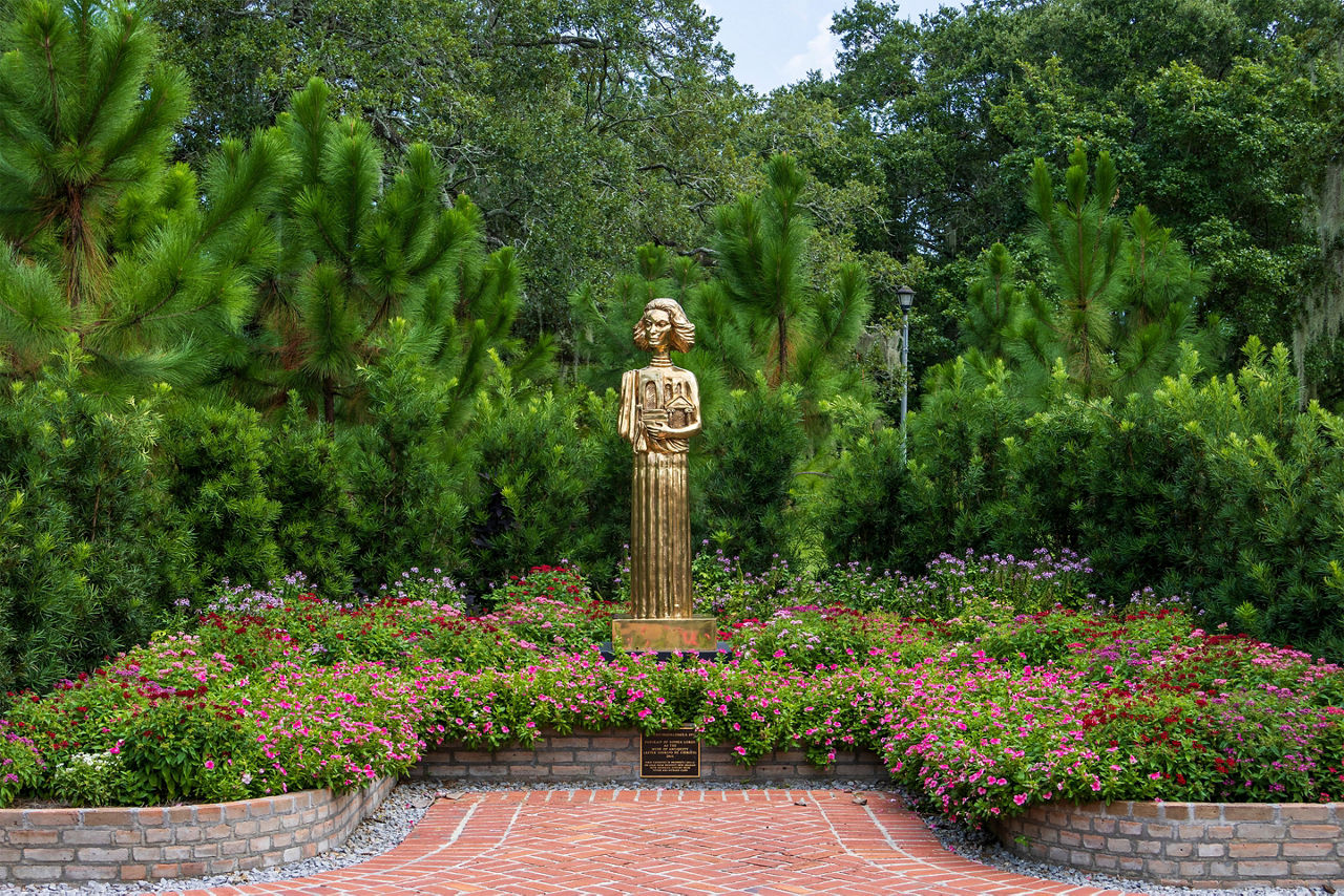 A gold statue of a woman in the garden at New Orleans Botanical Garden