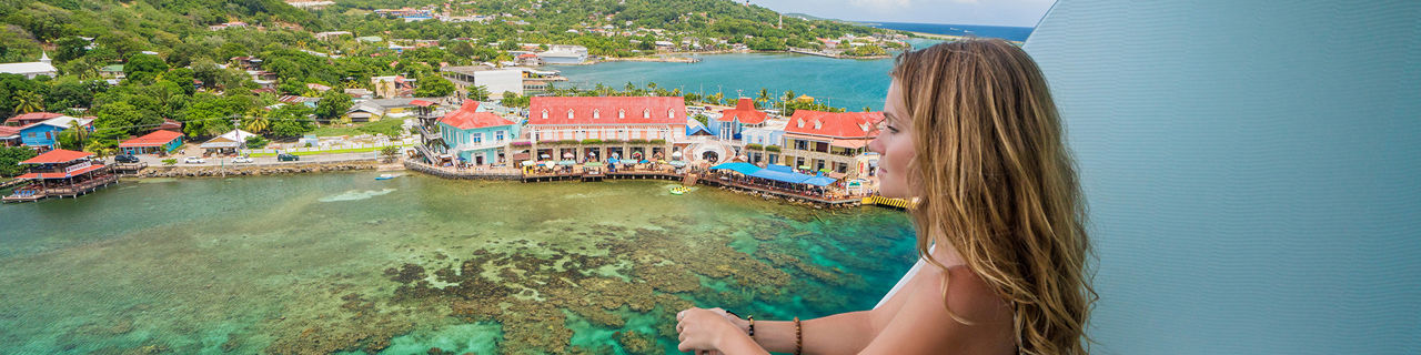 Woman looking at ocean from cruise ship in a white sun dress. The Caribbean.
