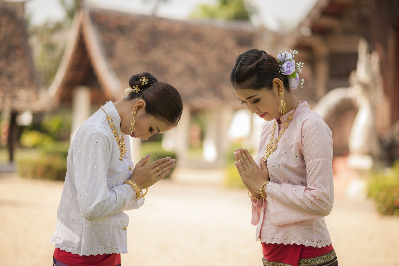 Two Thai women paying respect or wai