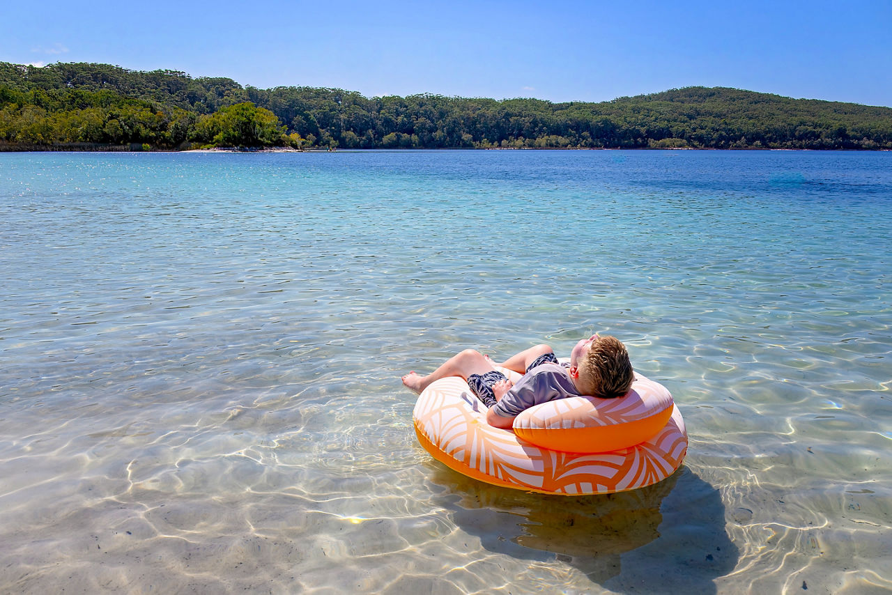 Boy relaxing, floating on Lake McKenzie, Boorangoora, K'gari Fraser Island