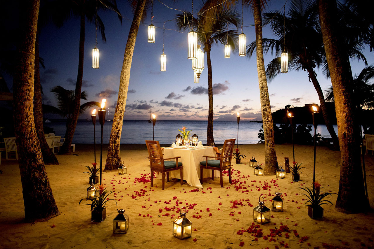 Romantic couple’s table for two on a beach at sunset. The Caribbean.