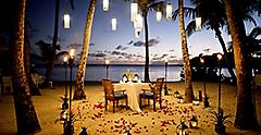 Romantic couple’s table for two on a beach at sunset. The Caribbean.