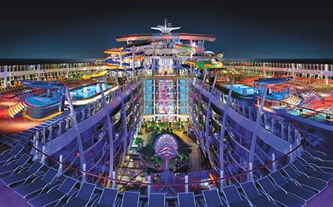 HM, Harmony of the Seas, OOH, wide panoramic view of top deck with the Perfect Storm water slides in center, night, nighttime, top deck with pools, Central Park below, night sky in background, purple, blue colors,