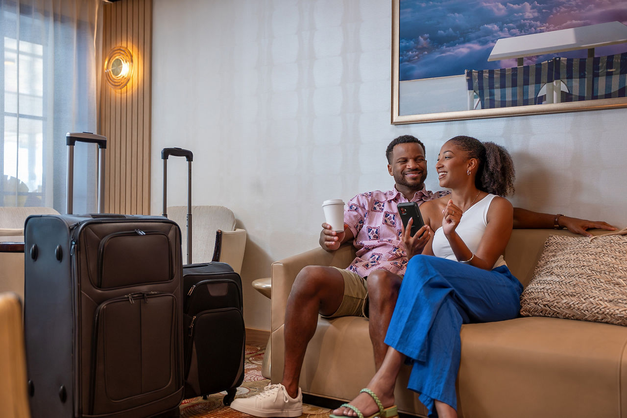 Couple sitting on couch with luggages beside.