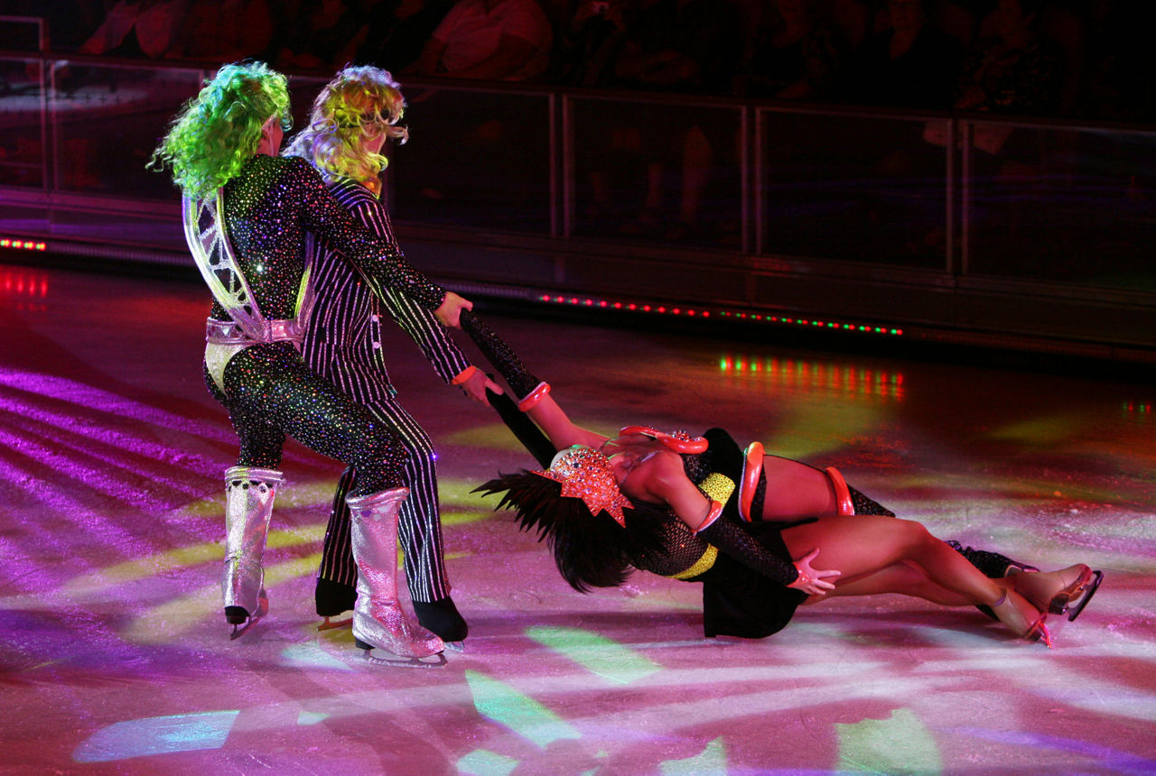 Couples swinging female skating performers during Ice Games show.