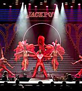 Performers in red costumes on stage during the Jackpot Cruise Show on Adventure of the Seas