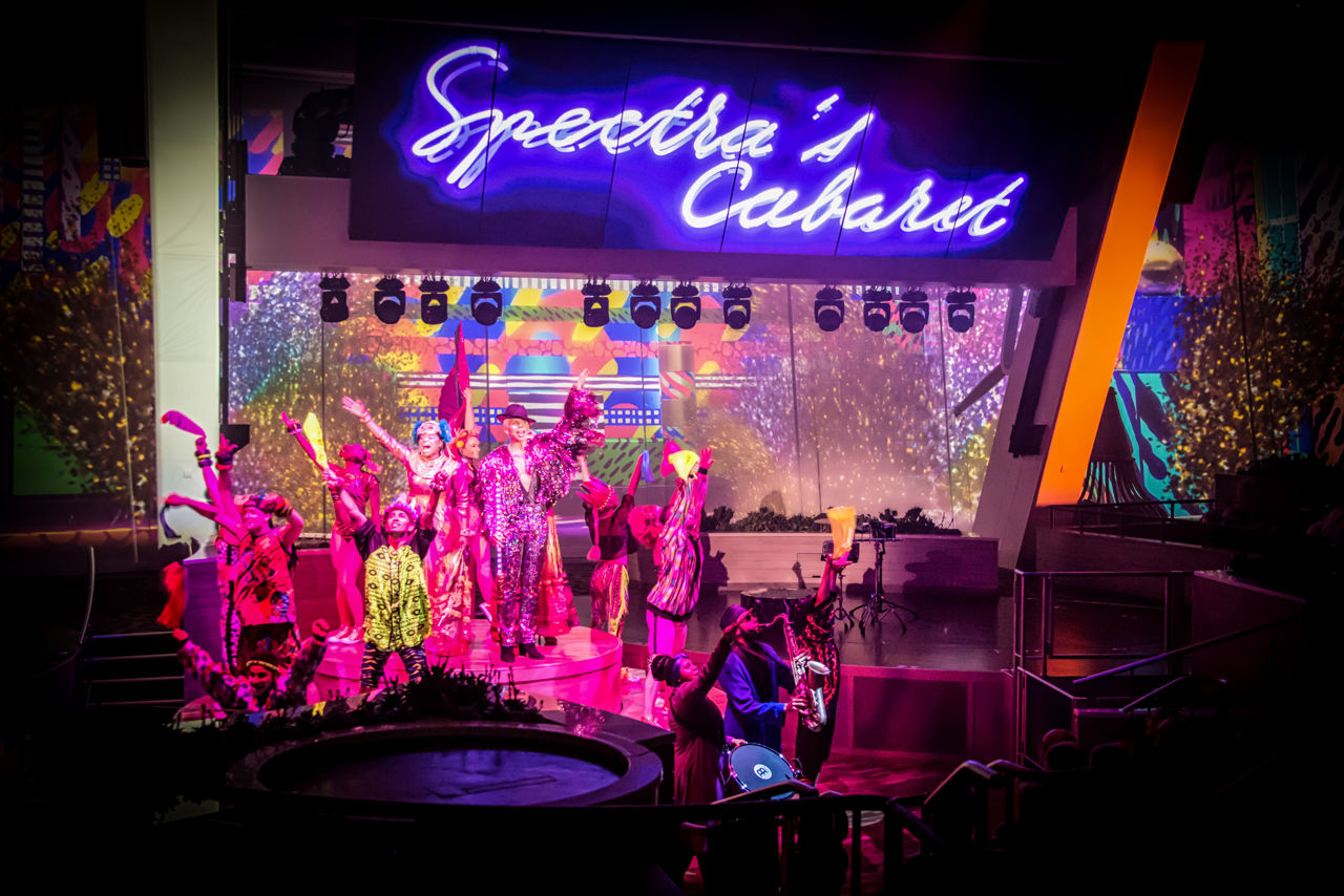 Performers on stage with pink lights at night show of Spectras Cabaret on Anthem.