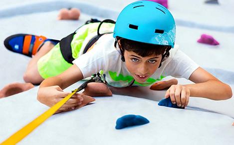 Young Boy Reaching the Top of the Rock Wall 