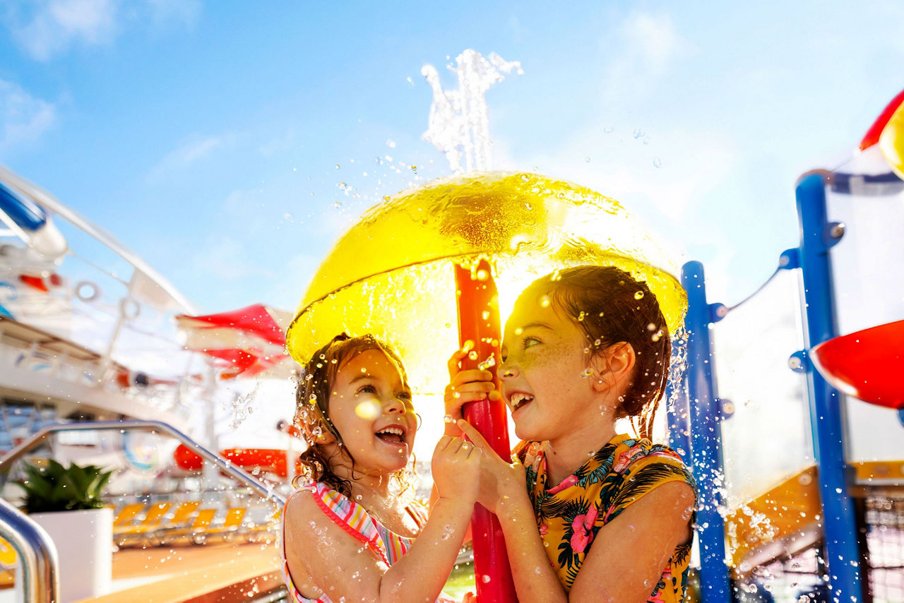 WN, Wonder of the Seas, two young girls under yellow dome fountain, SplashAway Bay, fun, kids, children, water droplets, spray,