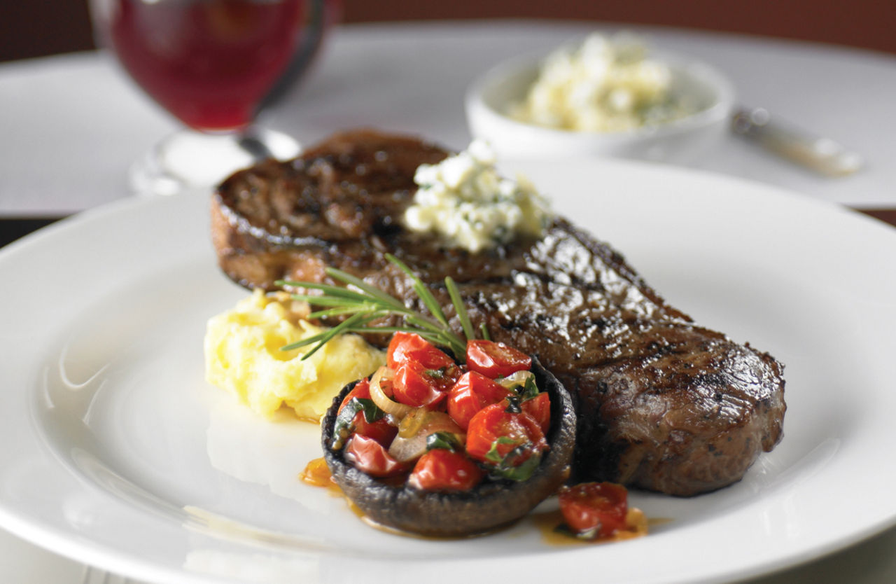 12 oz Grilled NY-Strip Steak served at the fine dining steakhouse, Chops Grille. One of the best cruise line restaurants.