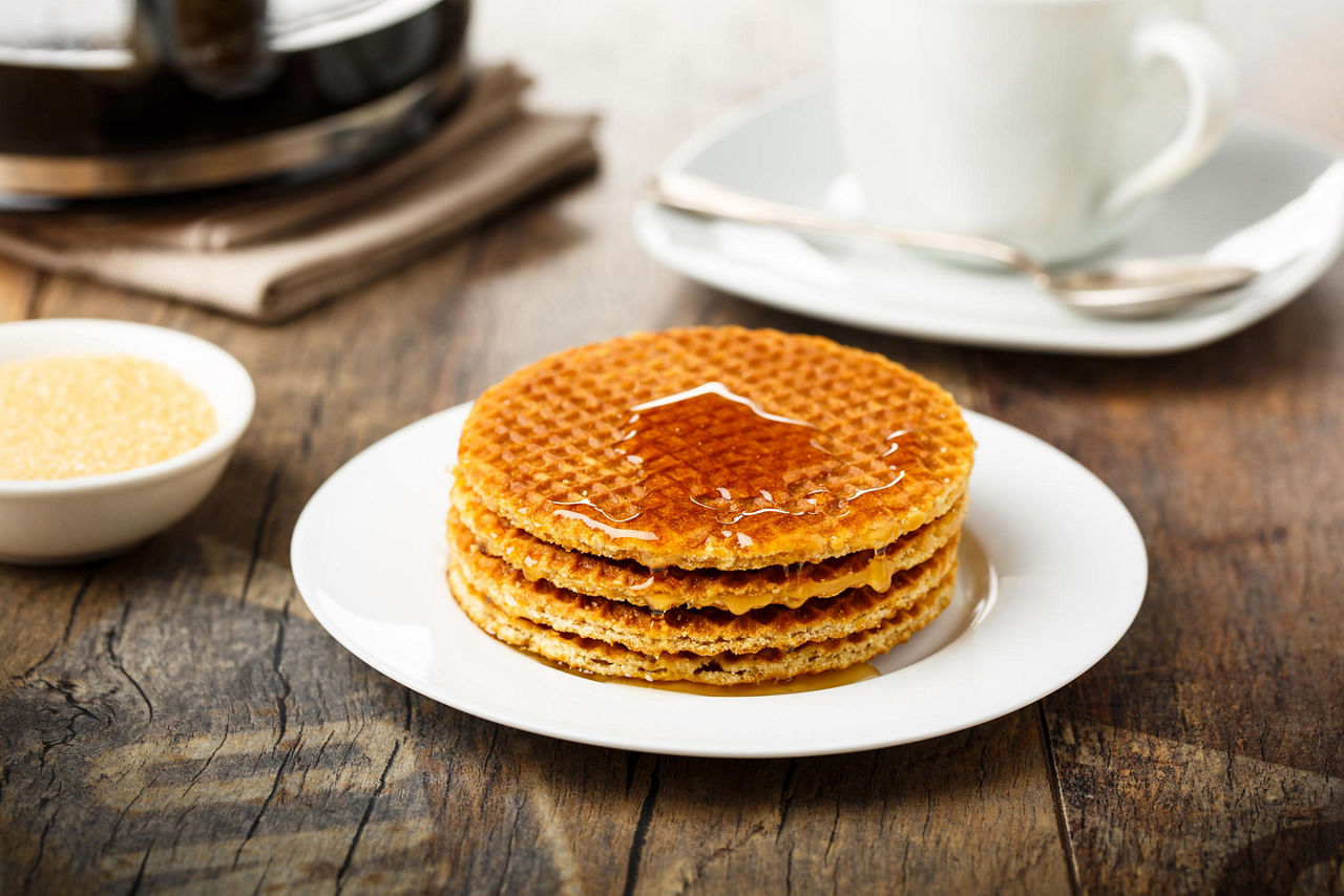 Stack of fresh Stroopwafels with honey and coffee, in a shop in Amsterdam, Netherlands
