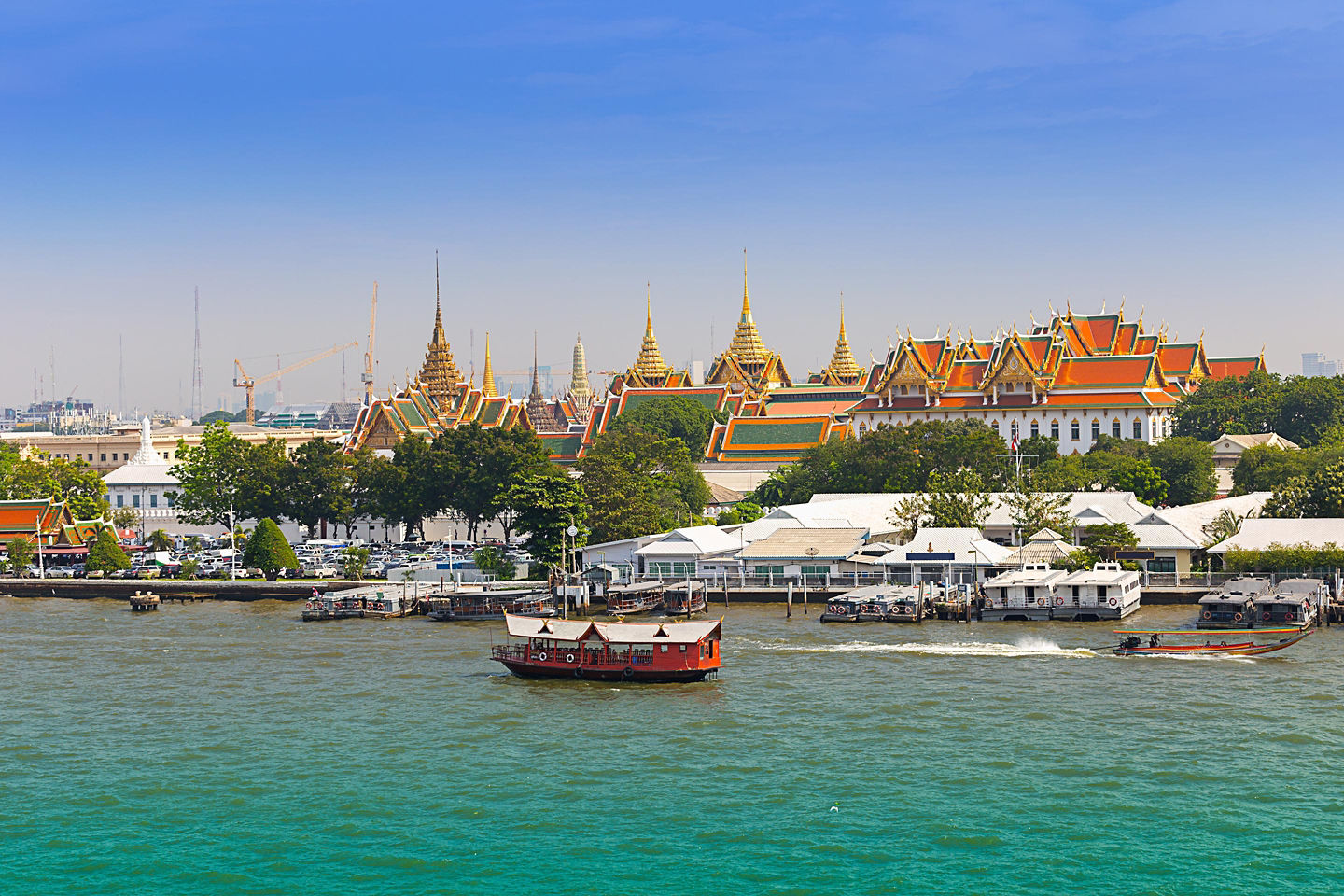 Boats travel along the Chao Phraya River, passing temples and city buildings under Bangkok’s bright sky. - Bangkok (Laemchabang), Thailand