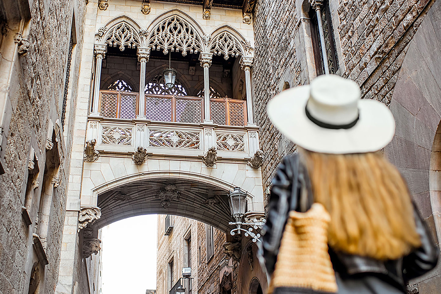 A narrow Gothic‑quarter street is lined with tall stone buildings and soft, warm light. - Barcelona, Spain
