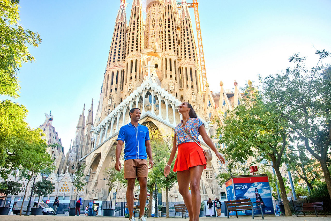 Couple walking in Barcelona Spain with la Sagrada Famila in the background, woman looking up in awe